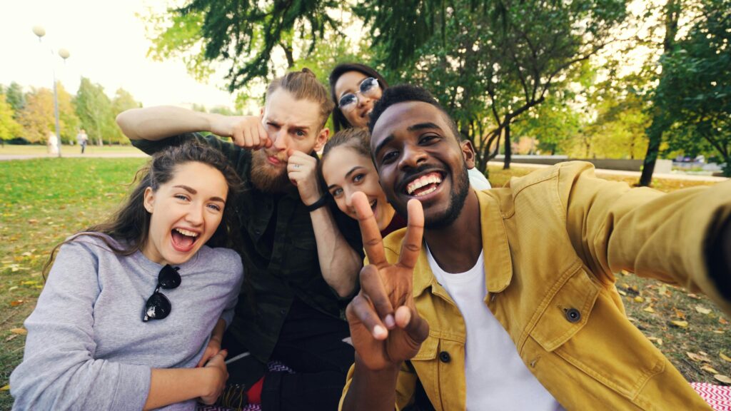 pexels-photo-36714243-36714243 A group of friends joyfully taking a selfie together outdoors in a park setting.